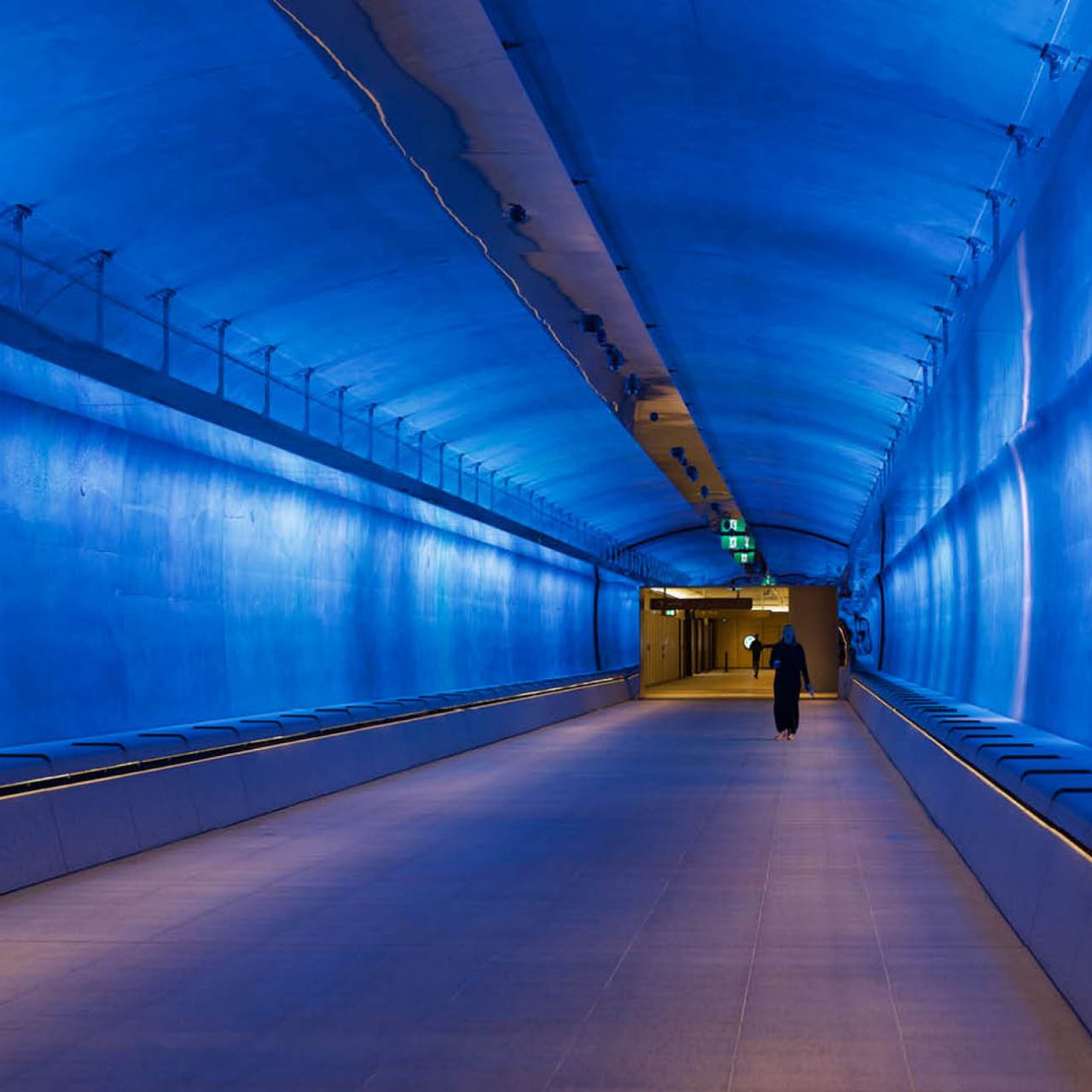 White and orange coloured lights inside the tunnel, featuring two people walking through