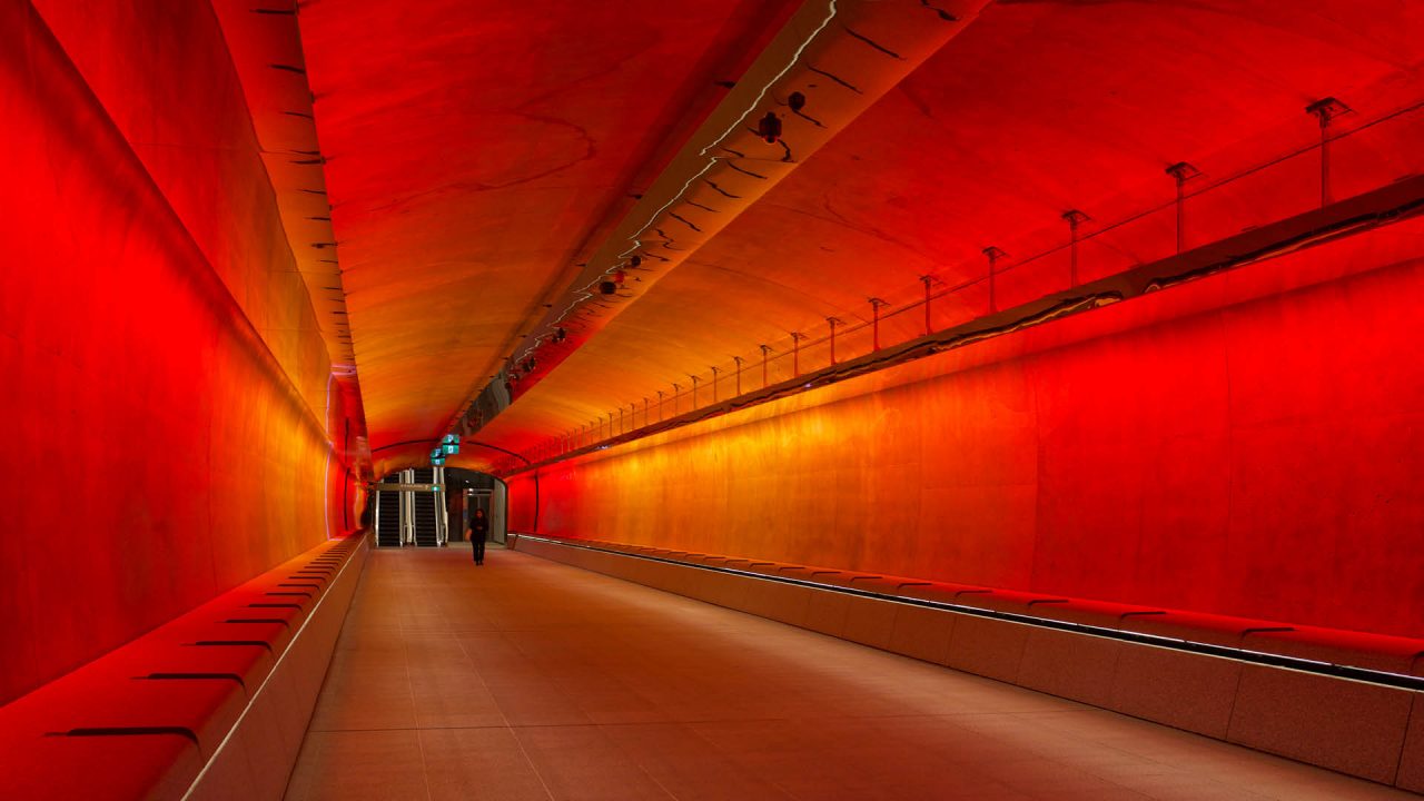 White and orange coloured lights inside the tunnel, featuring two people walking through