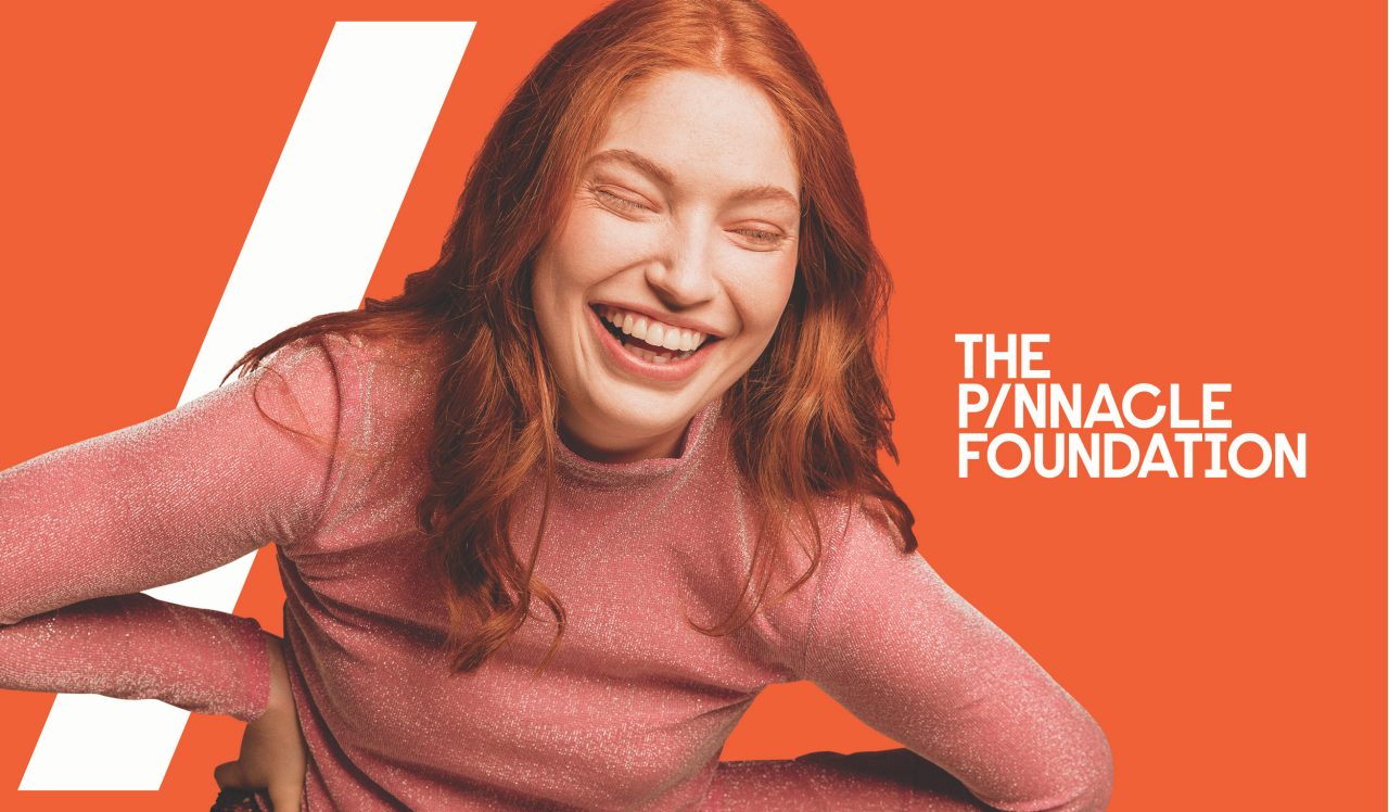 Girl smiling with The Pinnacle Foundation Logo